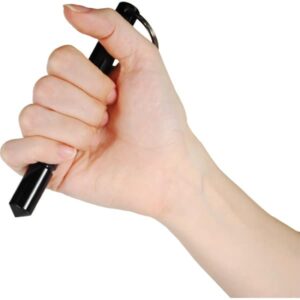 Demonstrating grip technique with thumb on top using black aluminum self defense keychain Kubotan.